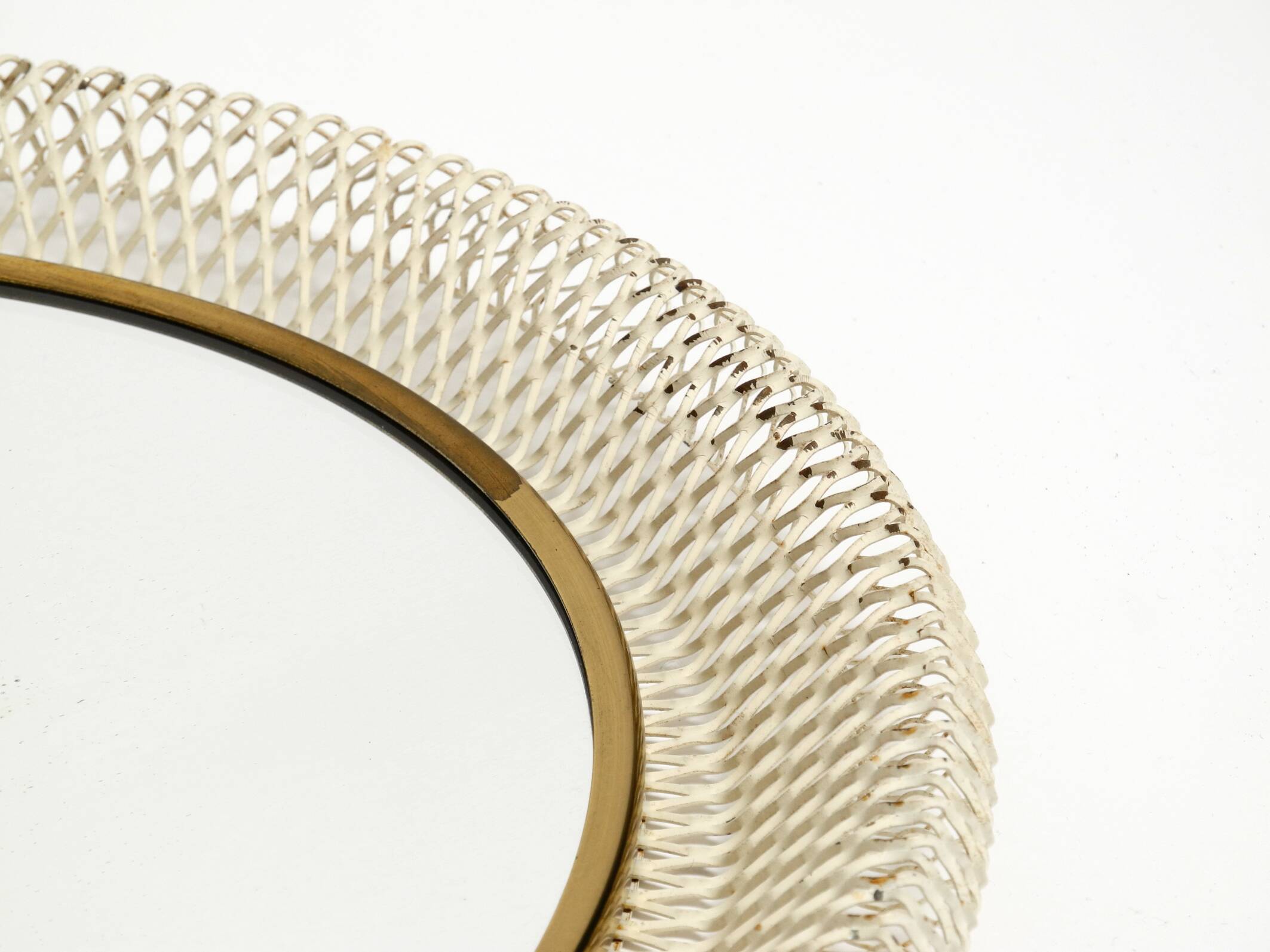 Mid Century Modern round wall mirror with a white expanded metal frame