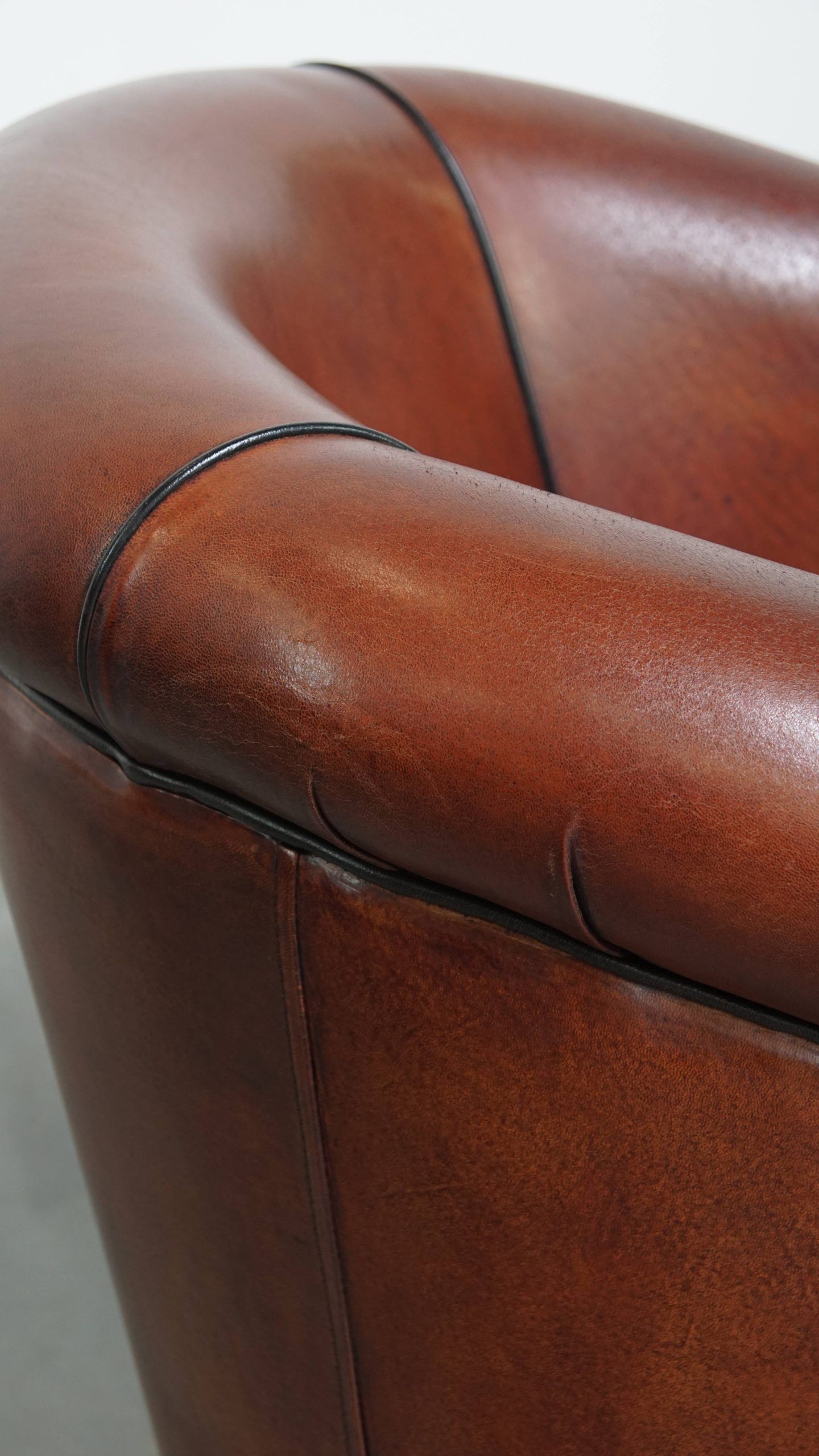 Sheepskin club armchair in a warm deep colour finished with black piping