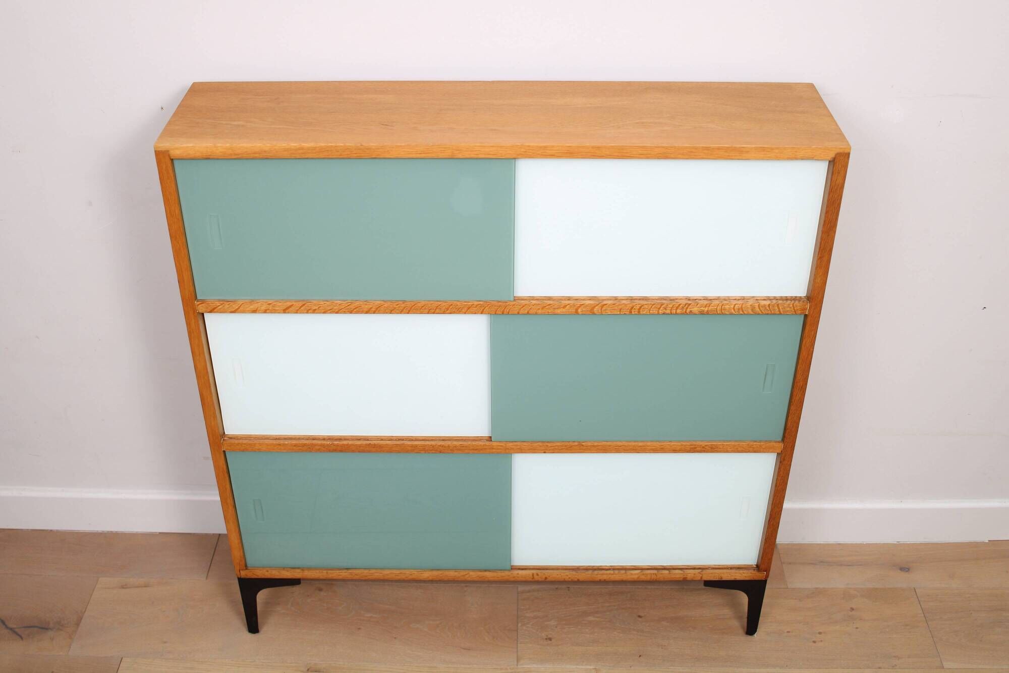 A vintage mid-century 3 tiered bookcase with glass sliding doors