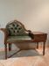 Antique carved wooden bench with green upholstered seat and backrest.