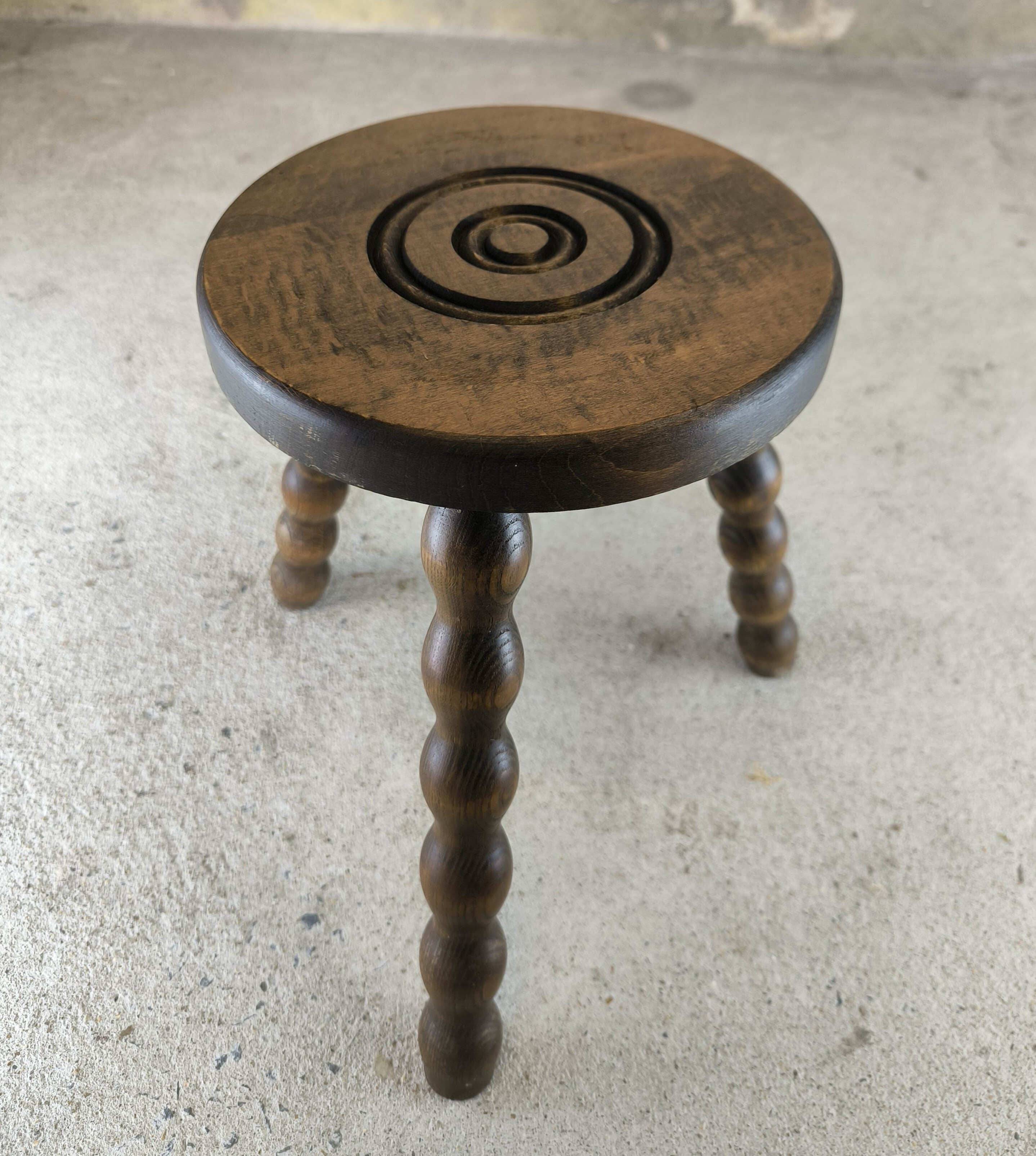 Small three-legged wooden stool with beaded feet.