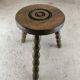 Small three-legged wooden stool with beaded feet.