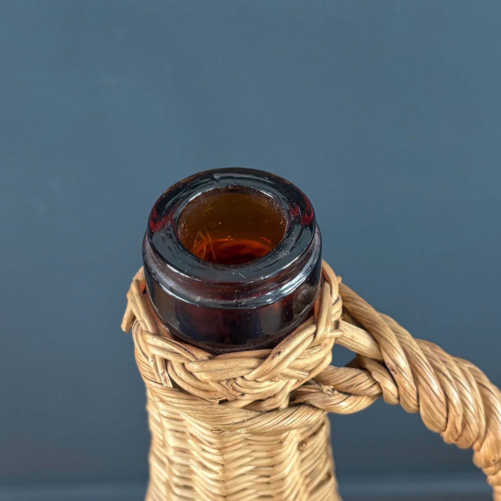 Amber glass bottle in its wicker handle basket.