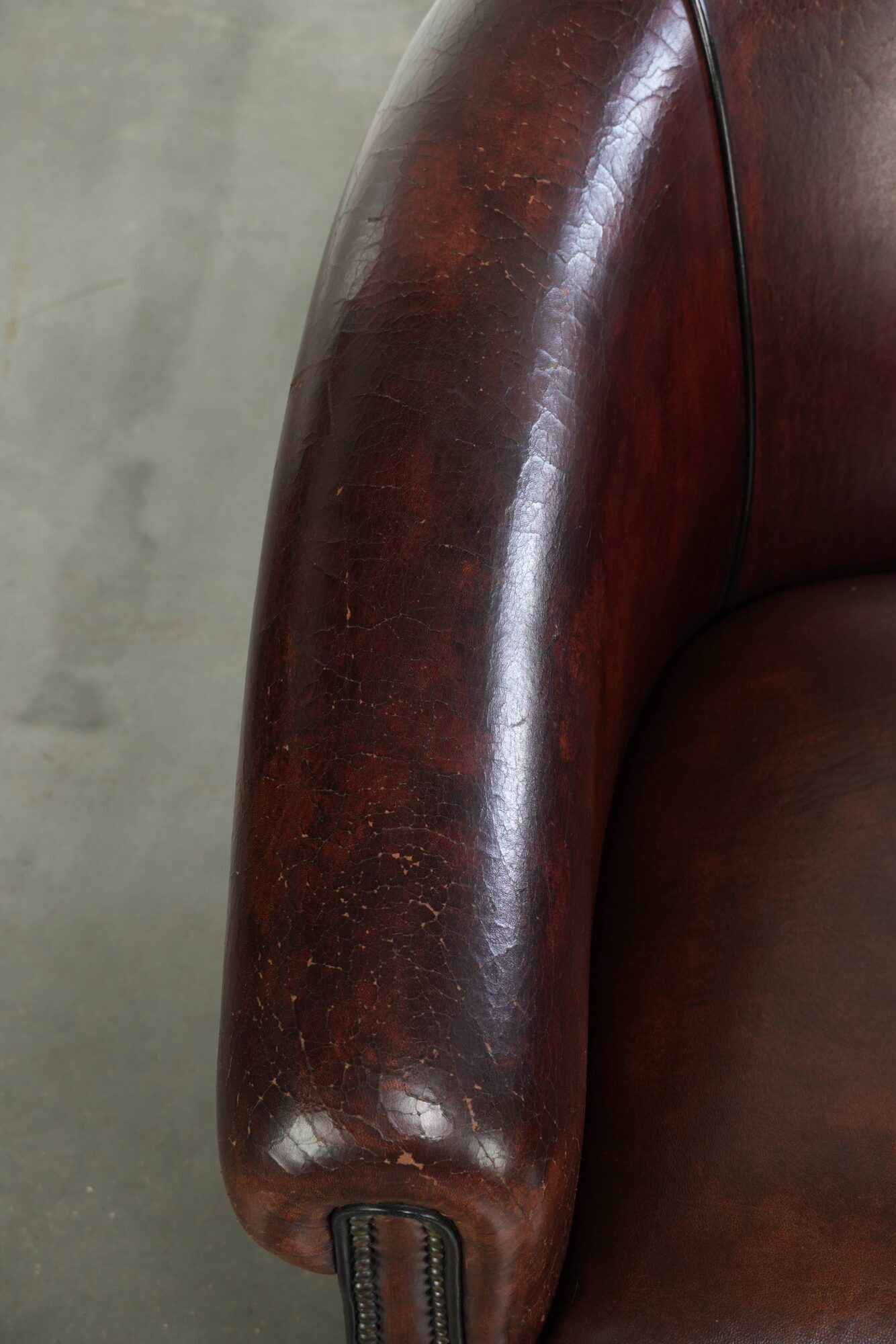 Vintage sheepskin club armchair with decorative nails and black piping