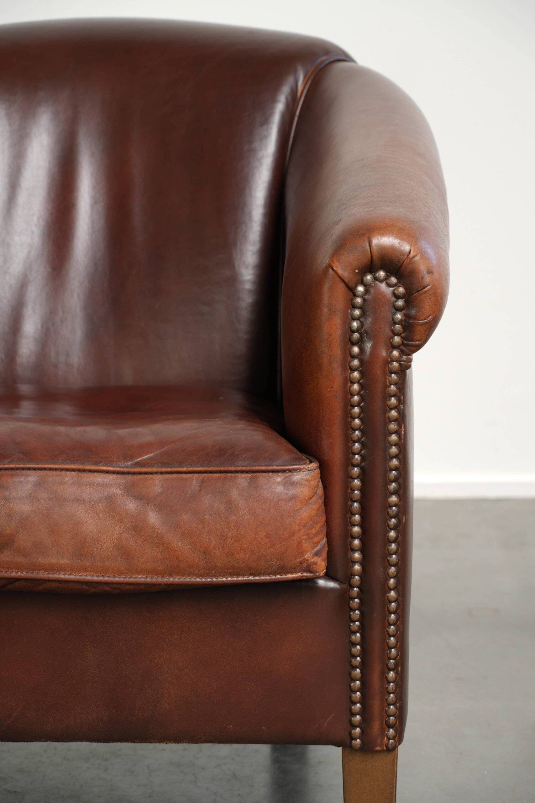 Characterful sheepskin club armchair in a dark cognac colour in English style