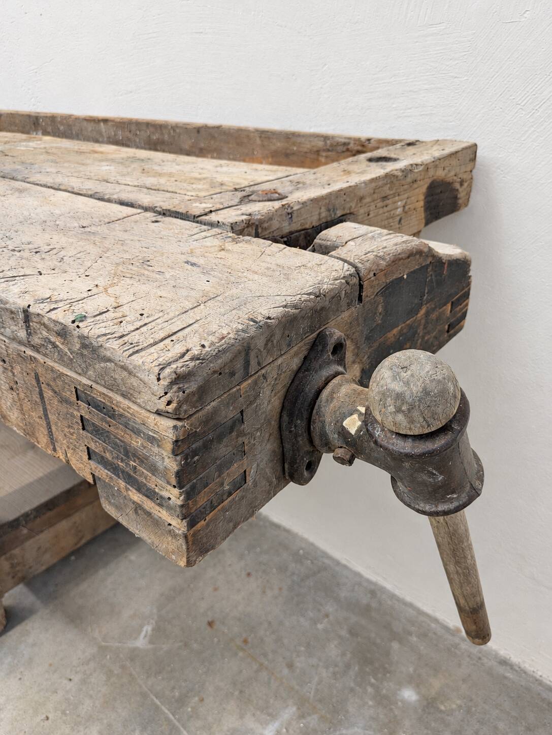 Antique wooden workbench with a vice and drawer.