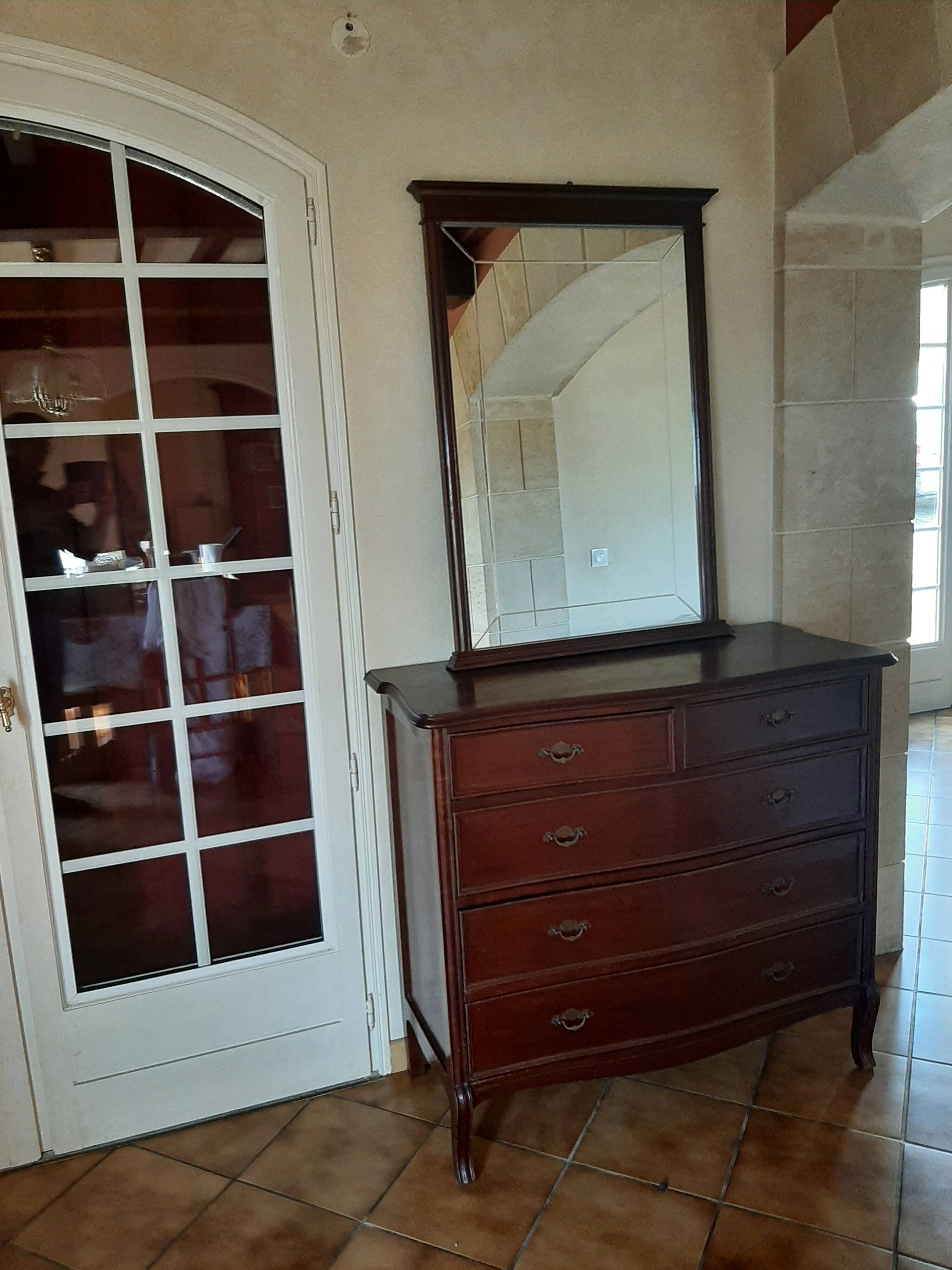Style set: bevelled mirror and curved wooden chest of drawers.