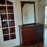 Style set: bevelled mirror and curved wooden chest of drawers.