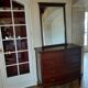 Style set: bevelled mirror and curved wooden chest of drawers.