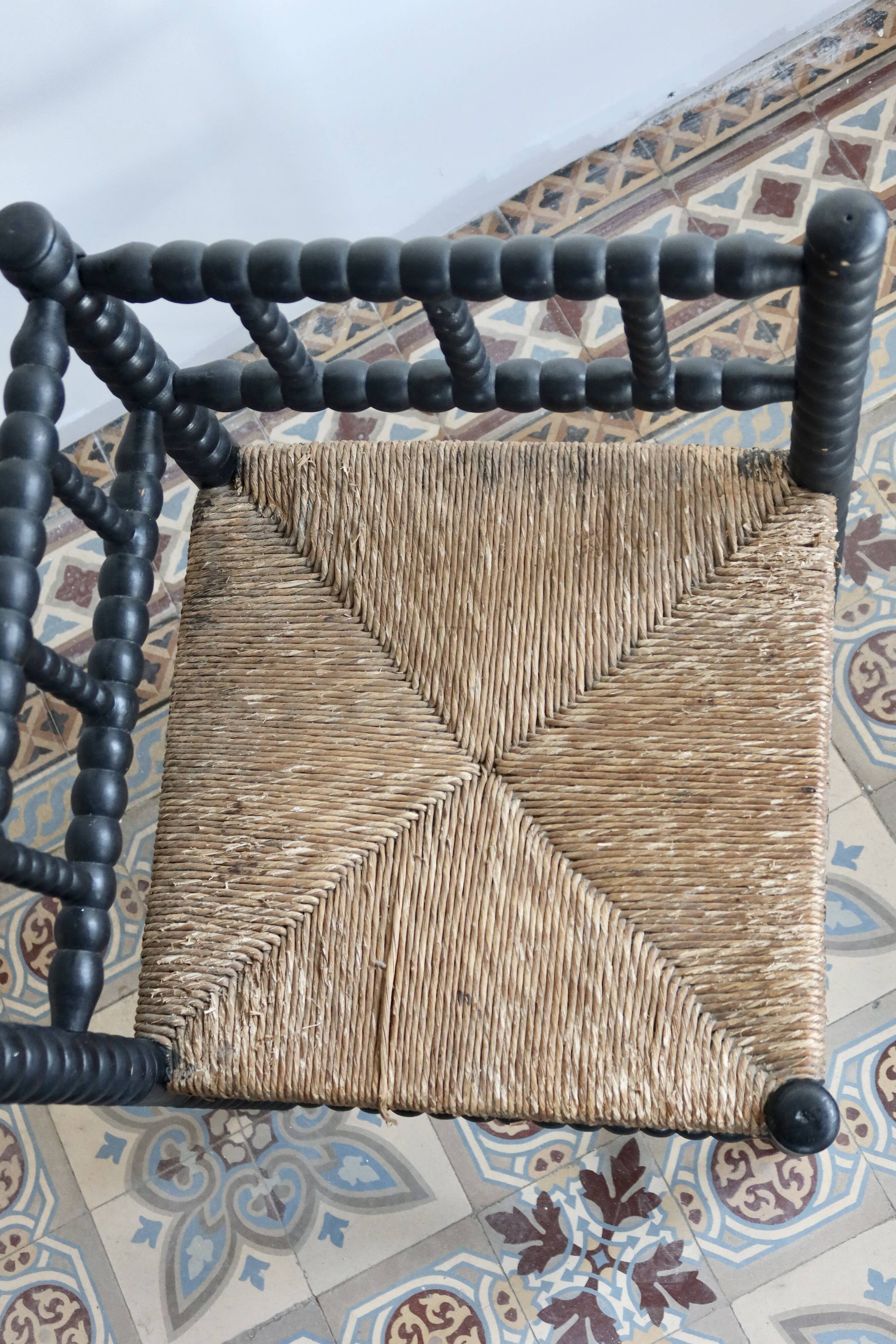 Antique black turned wood corner chair with a straw seat.