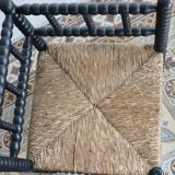 Antique black turned wood corner chair with a straw seat.