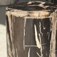Black petrified wood side table with beige stripes and a semicircular shape.