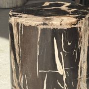 Black petrified wood side table with beige stripes and a semicircular shape.