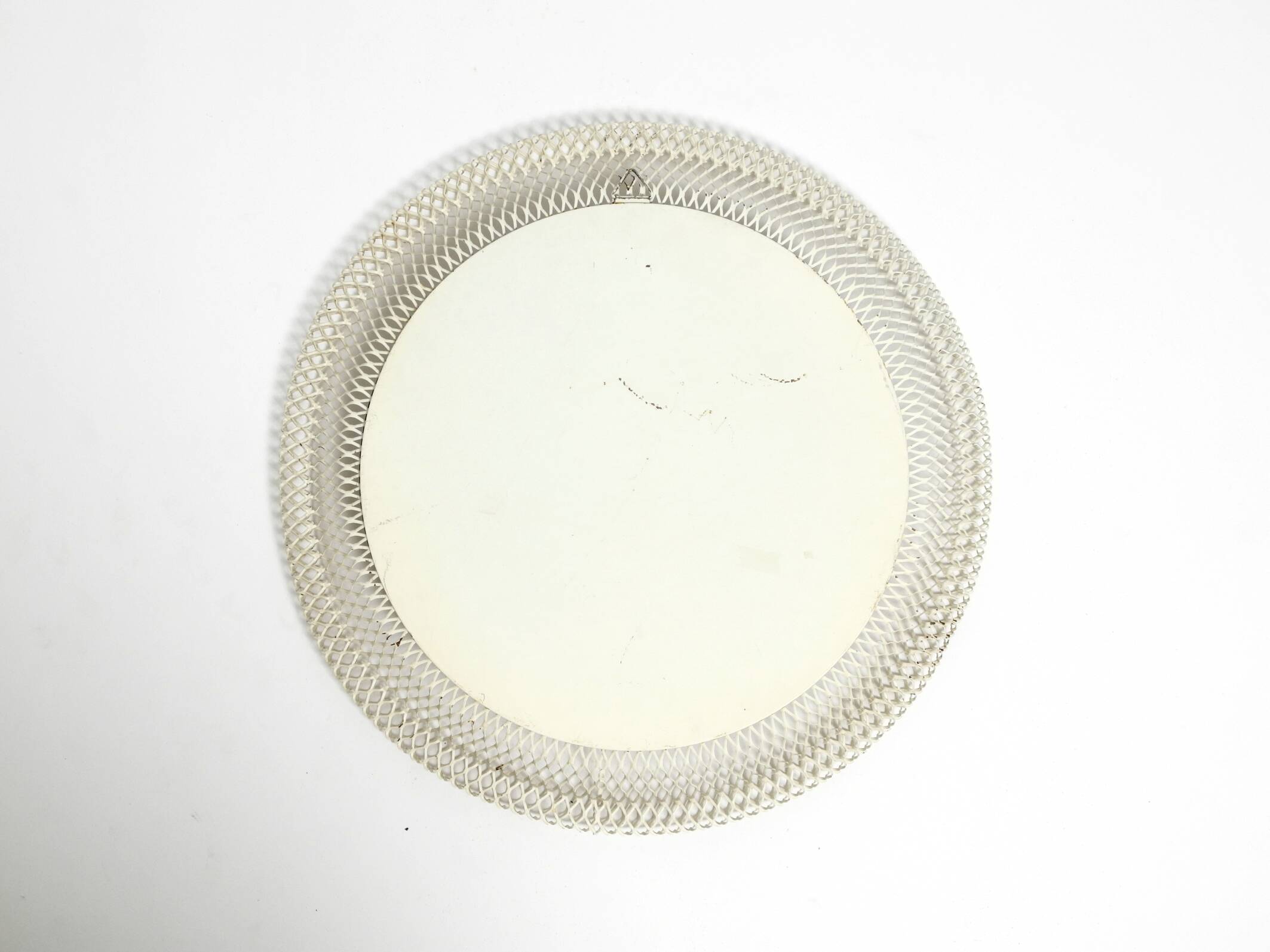 Mid Century Modern round wall mirror with a white expanded metal frame