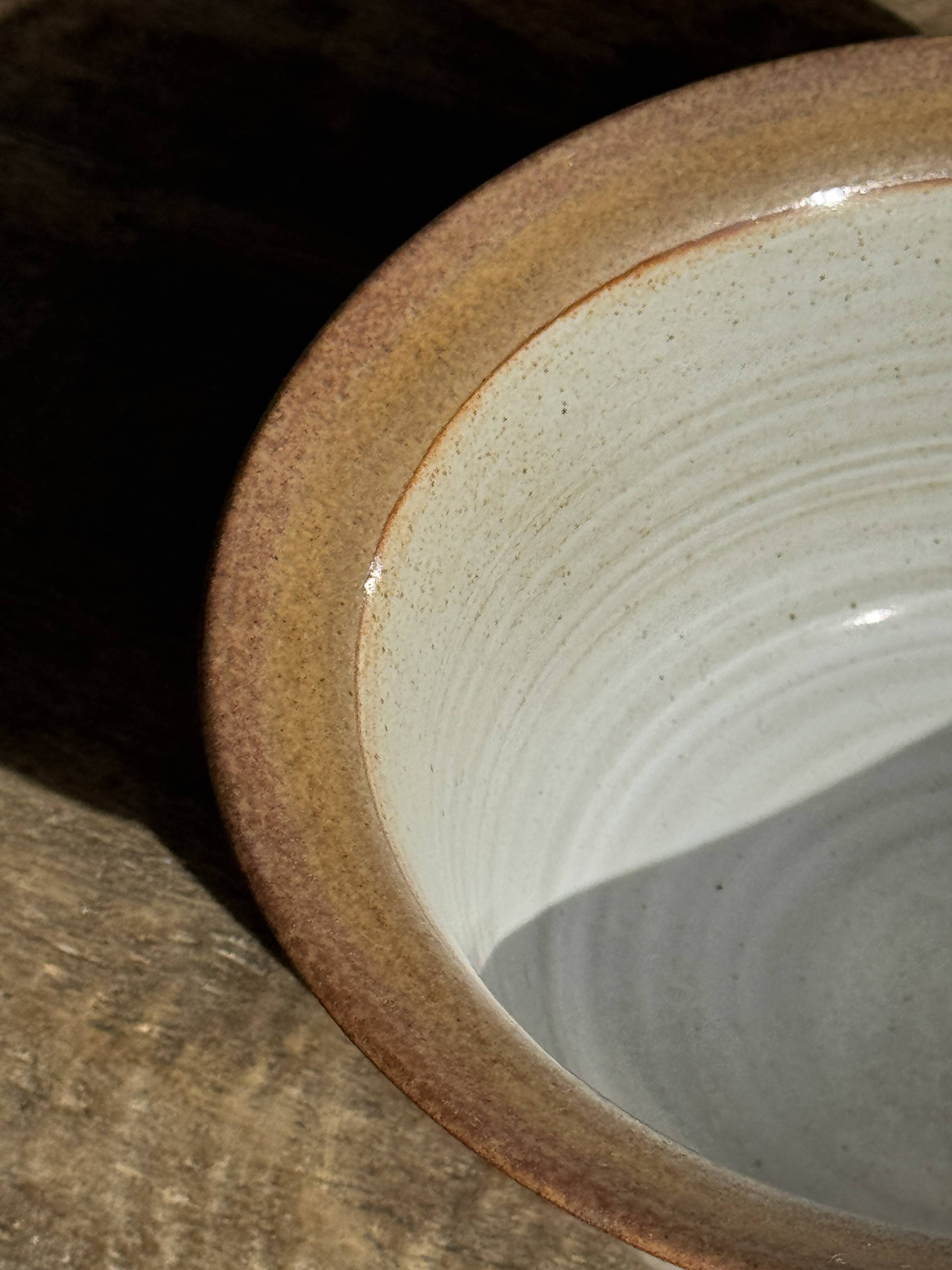 Small thick stoneware bowl with a stylised flower pattern in white on the outside, b