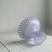 Purple glass pedestal bowl with wavy border and relief pattern.