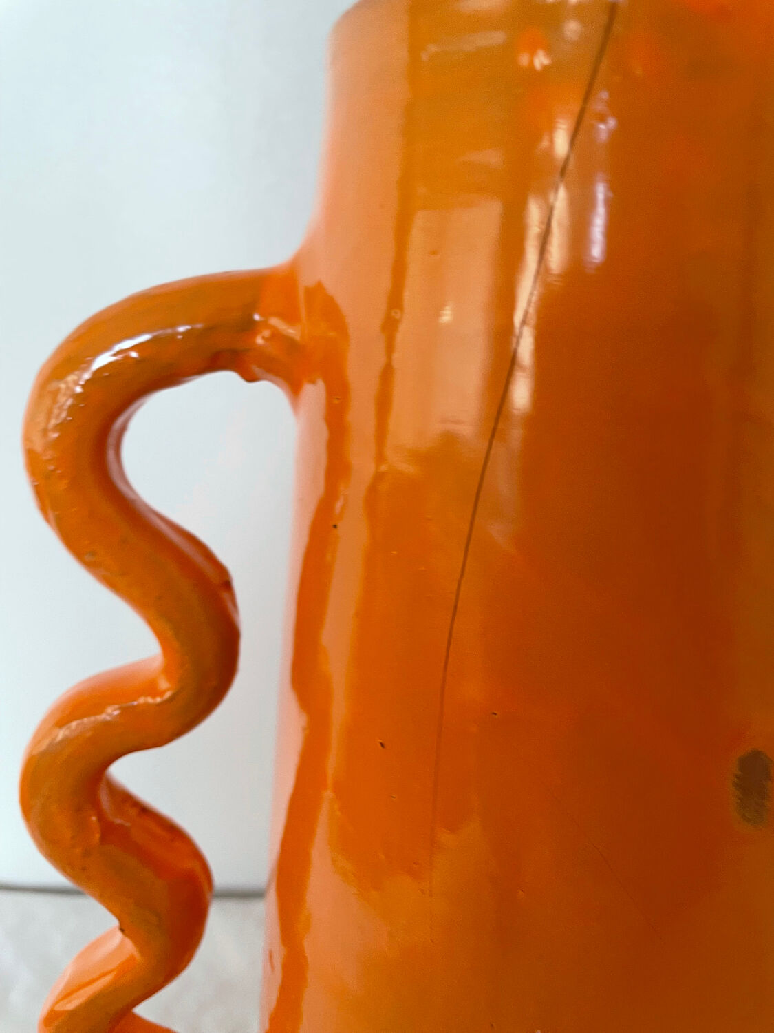 Handmade abstract orange ceramic vase with wavy handles