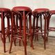 Series of 9 bistro bar stools in curved wooden restaurant sitting red fabric