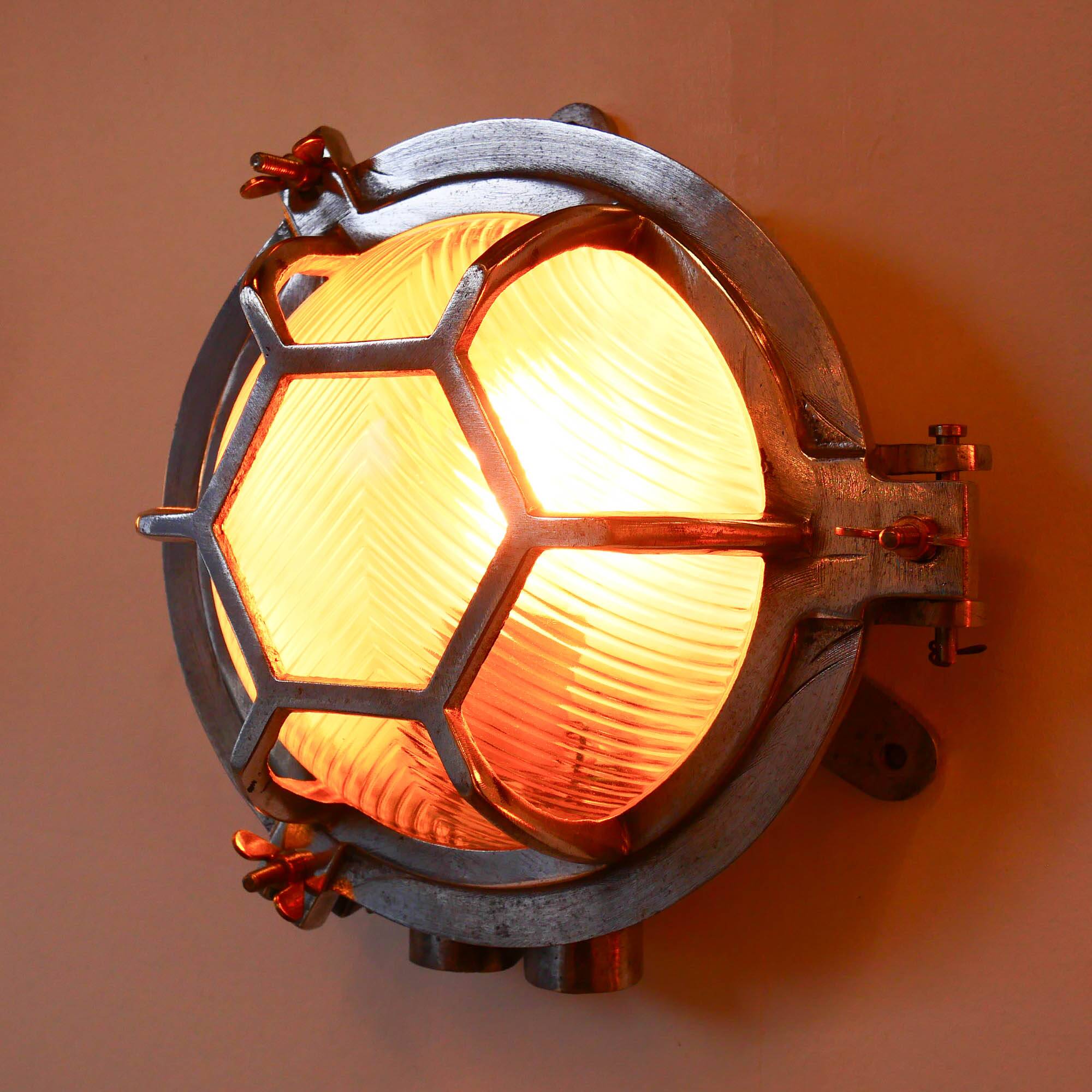 Old cast aluminum wall light with hexagonal grid and wide streaked glass.