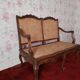 Antique carved solid wood bench with wicker caning.