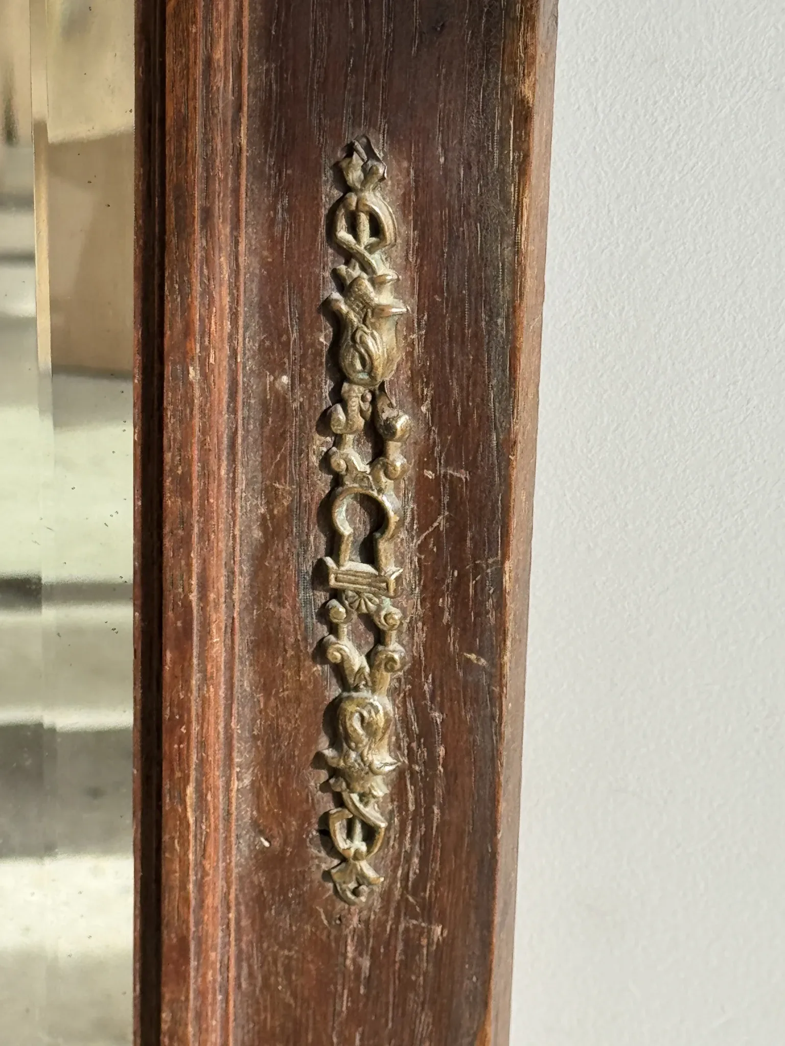 Antique mirror door (left) of a brown oak wardrobe with bevelled glass.