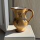 Large antique handmade ochre yellow jug with a pink flower pattern.