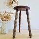 Antique tripod stool with turned wooden legs and leather seat.
