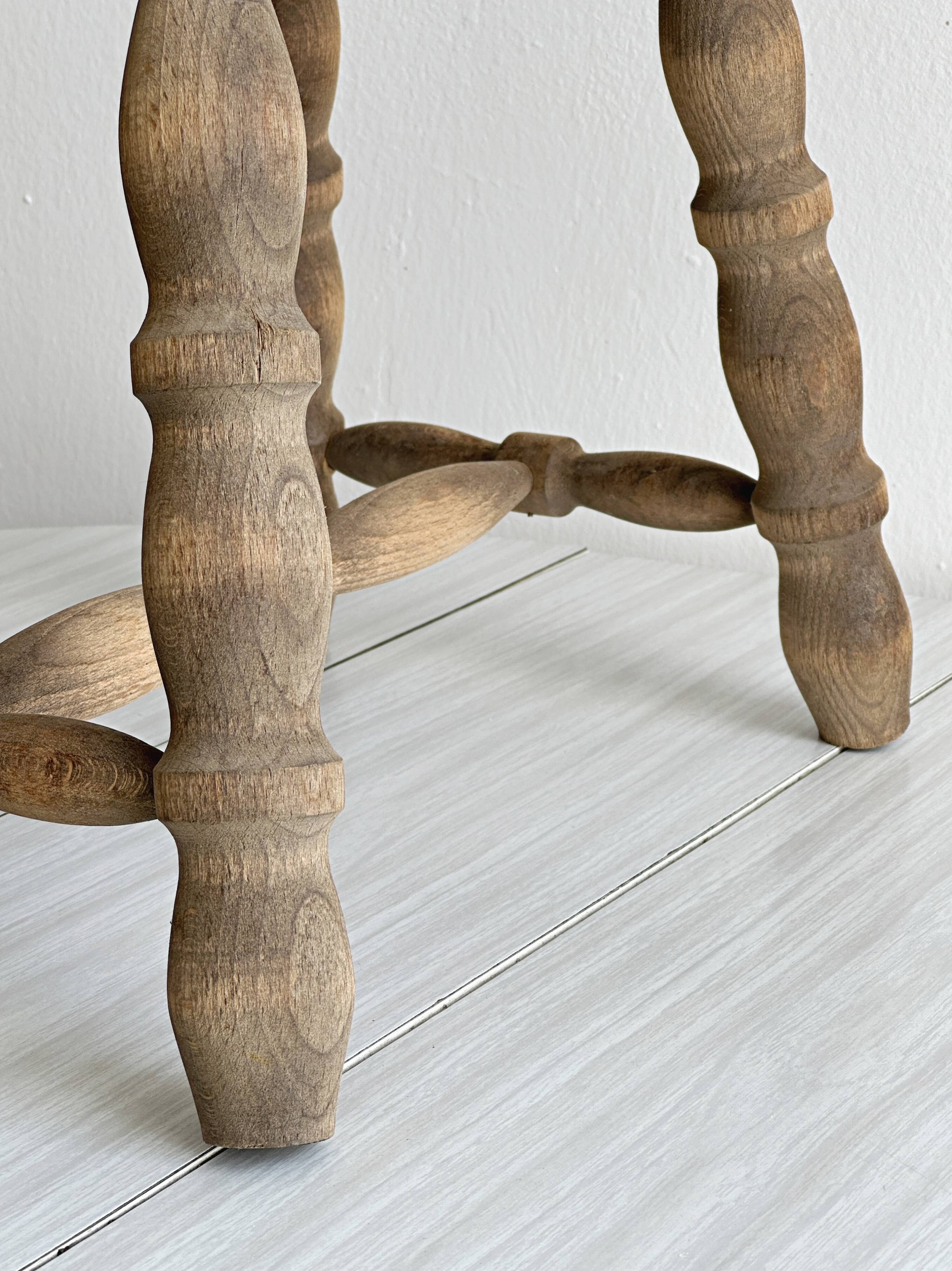 Antique wooden stool with four turned legs.