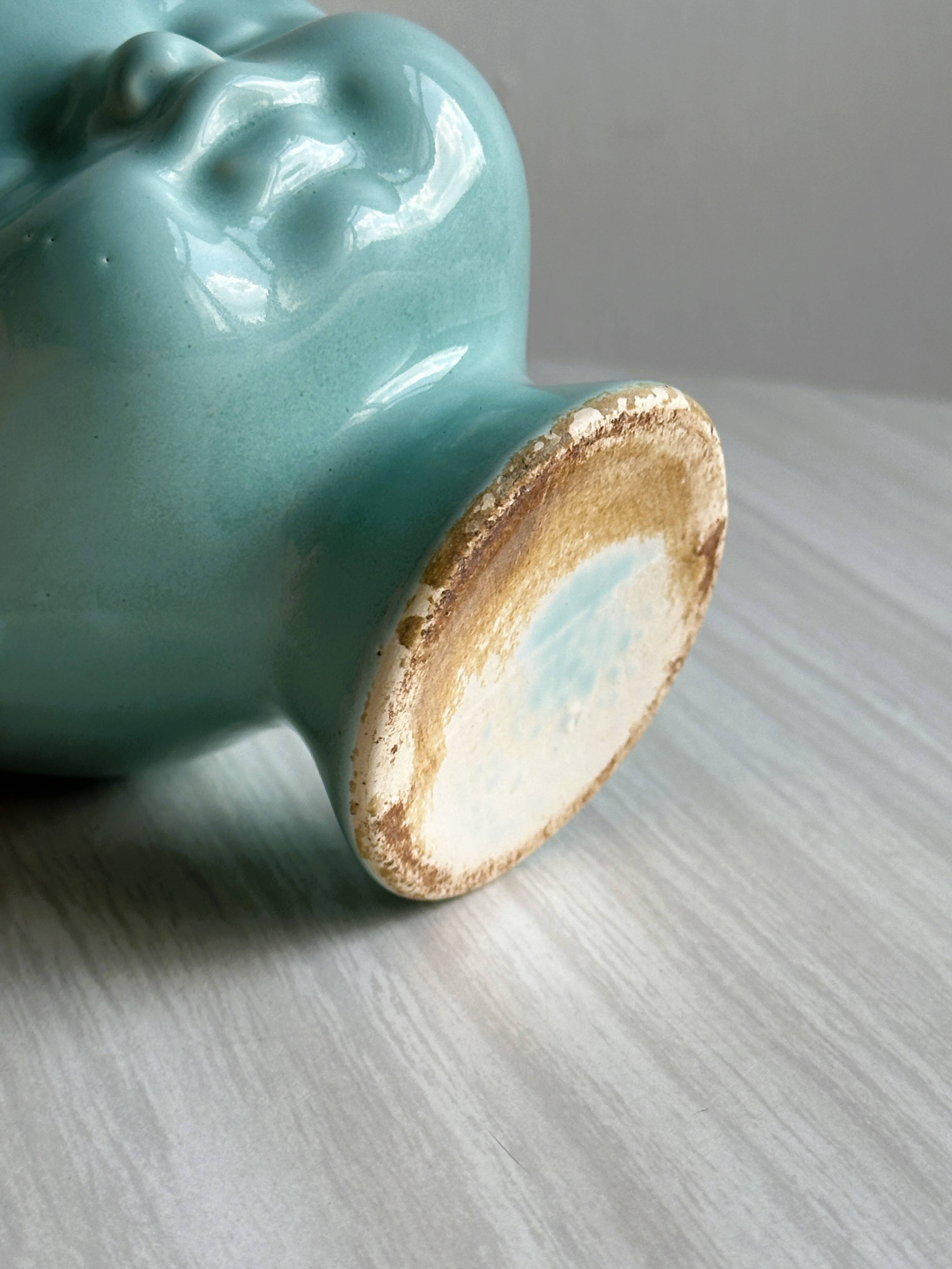 Turquoise plant pot in the shape of a vintage doll's head.