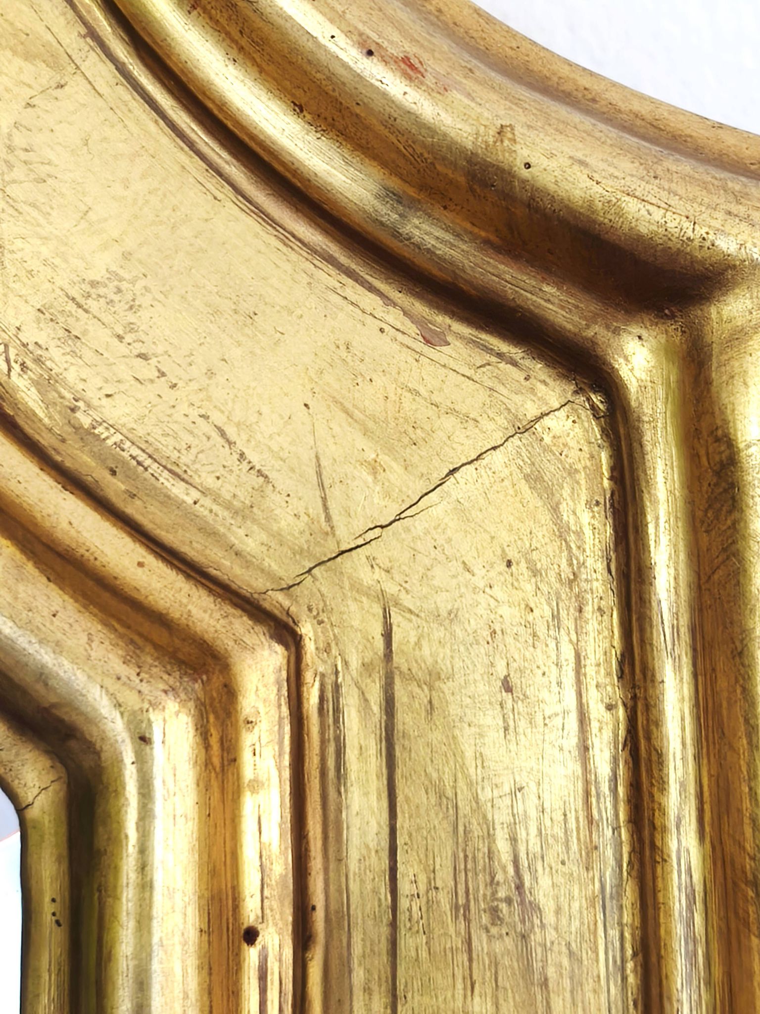 Florentine arched mirror in gilded wood with gold leaf.