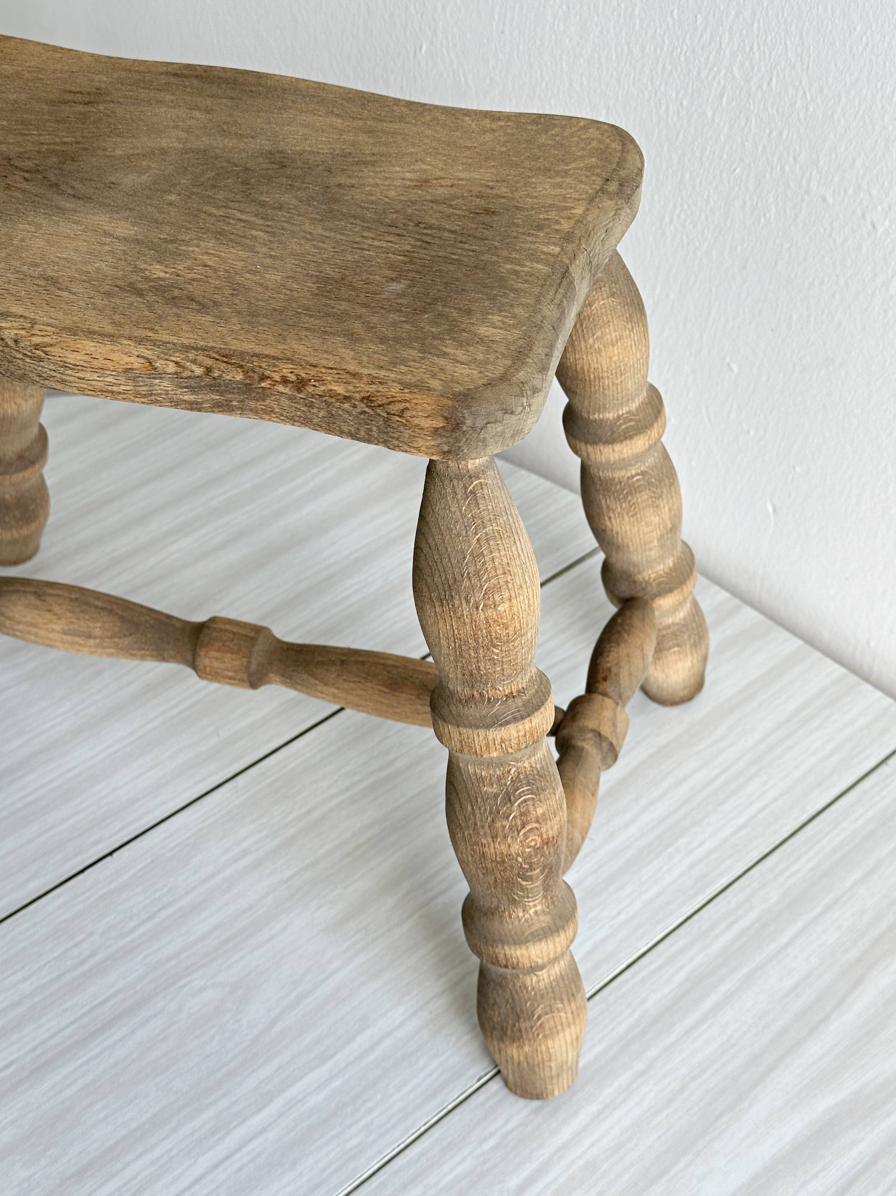 Antique wooden stool with four turned legs.