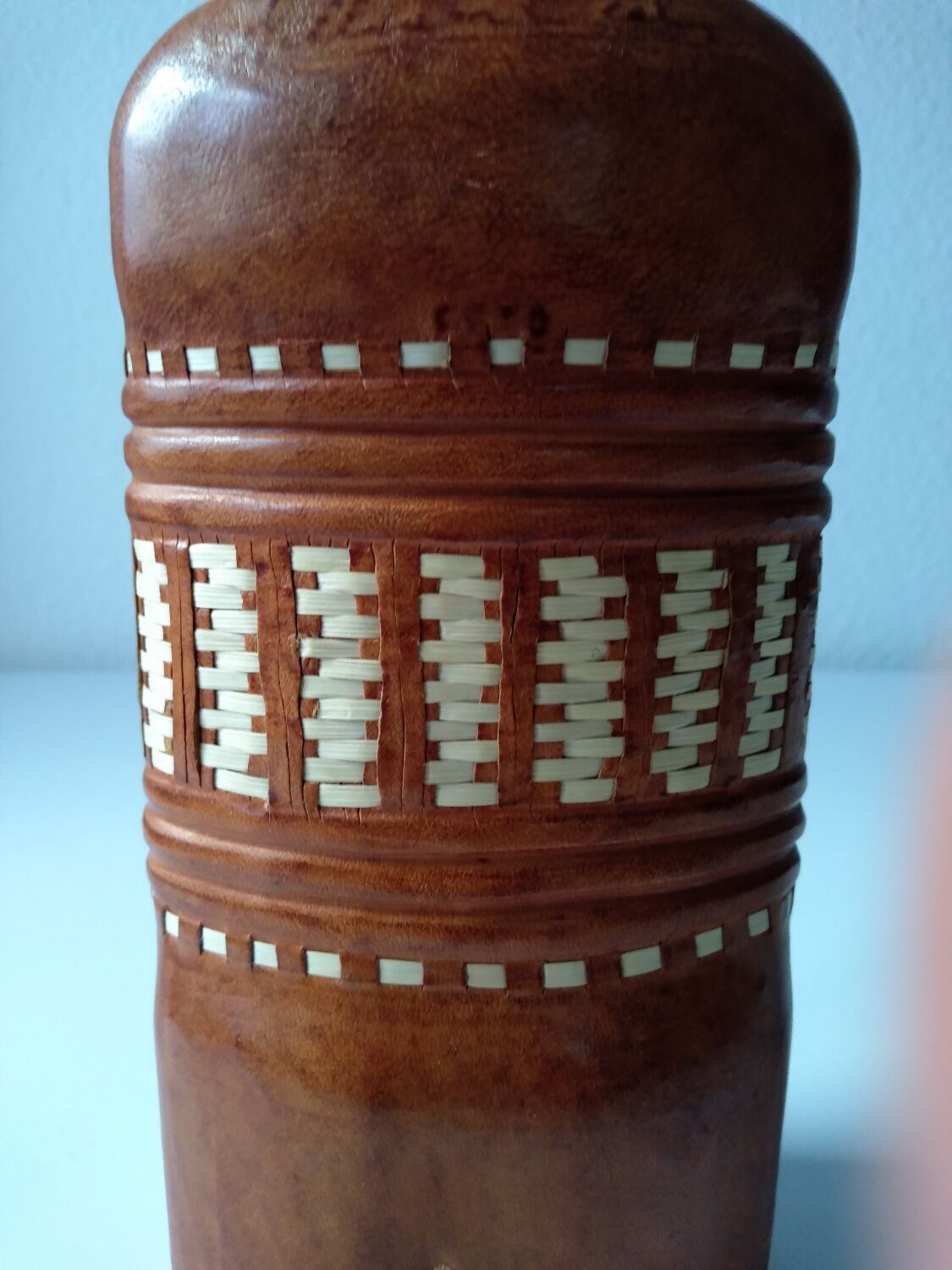 Vintage glass bottle covered with light brown leather and wicker