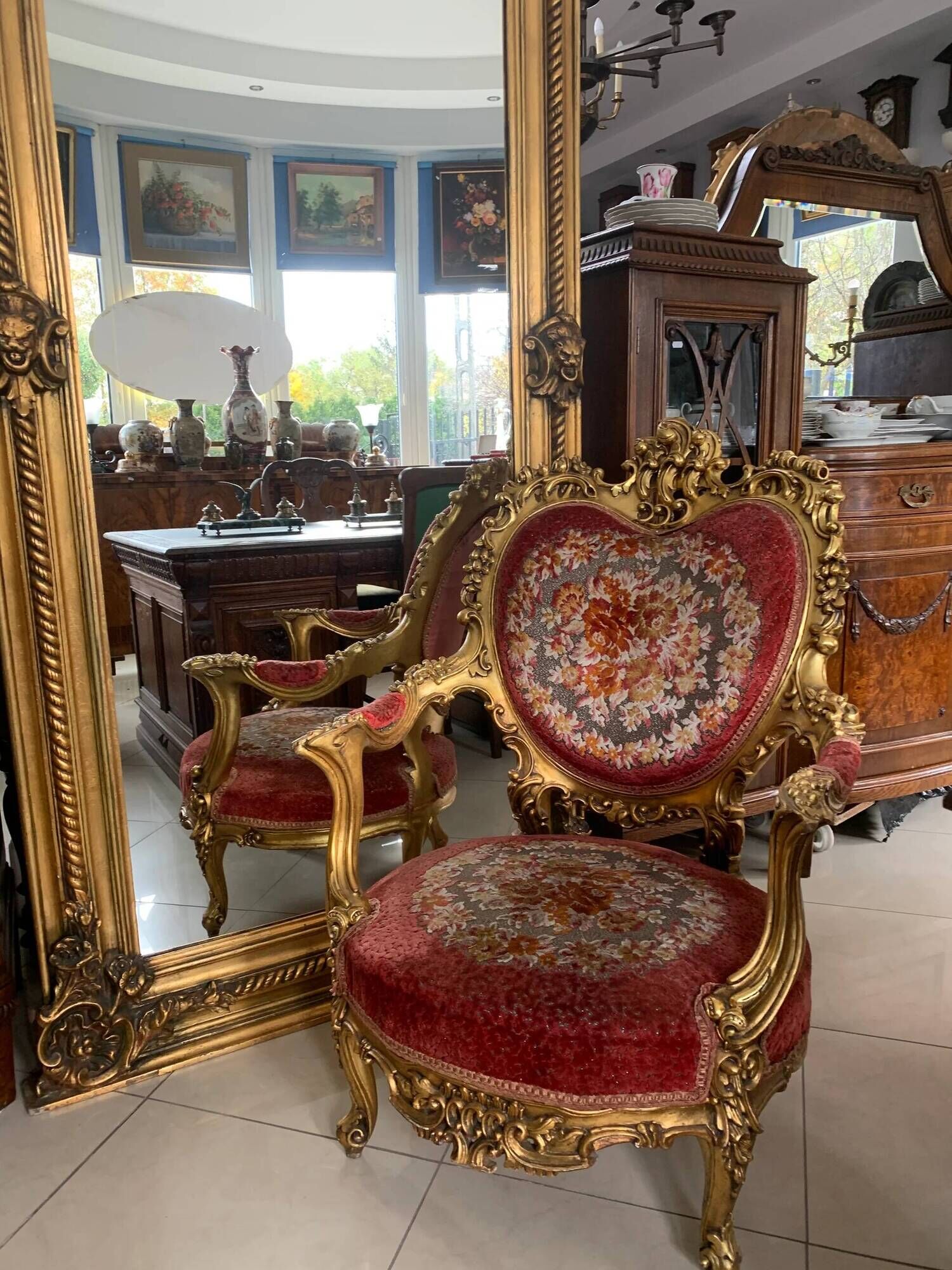 French palace mirror with bow and lion heads, gilded frame.