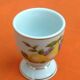 White porcelain egg cup decorated with pears / grapes.