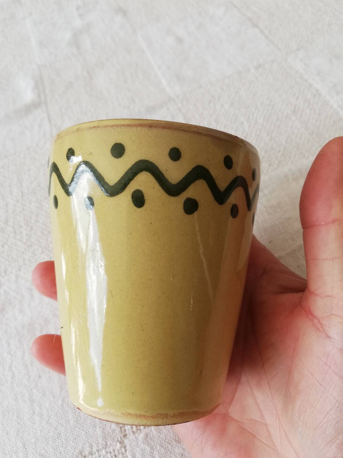 Mustard-colored ceramic cup or glass with green decor