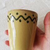 Mustard-colored ceramic cup or glass with green decor