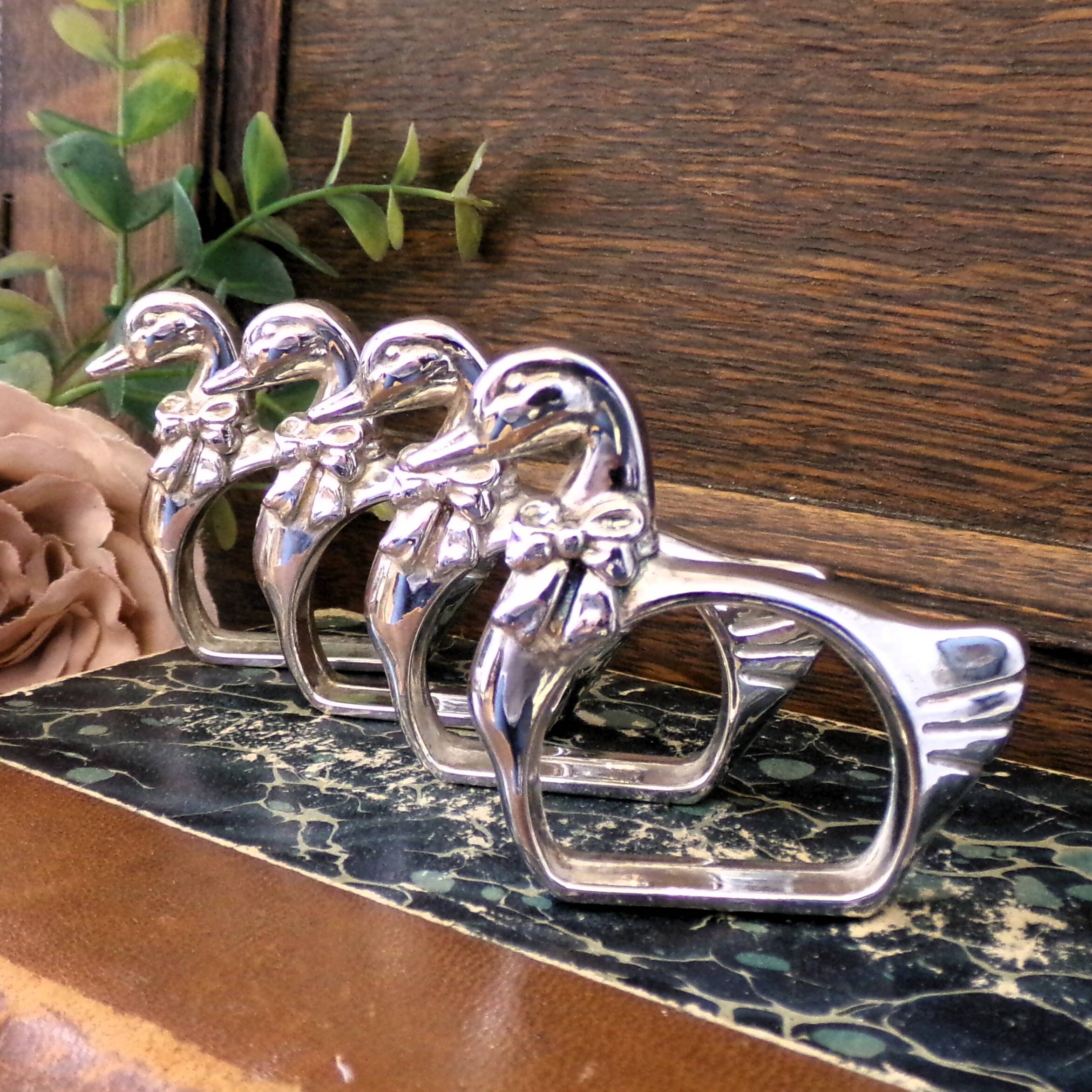 Four silver-plated napkin rings in the shape of a duck/goose