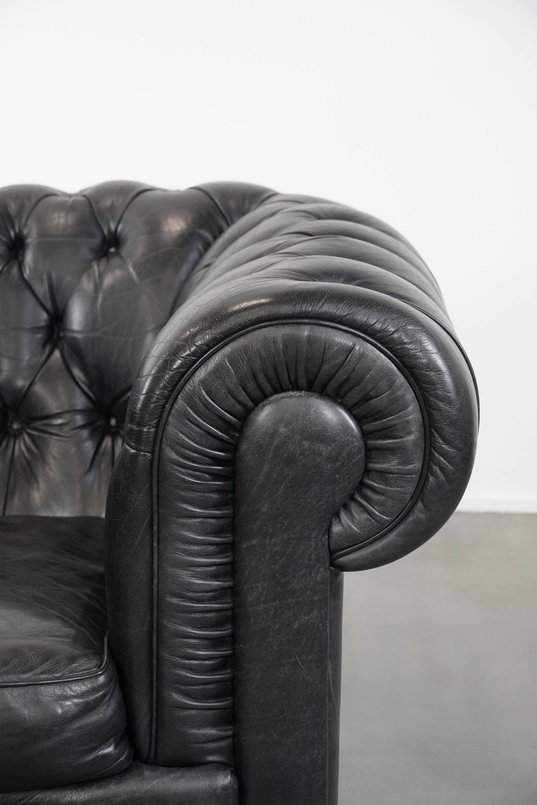 Comfortable black chesterfield armchair made of cowhide leather