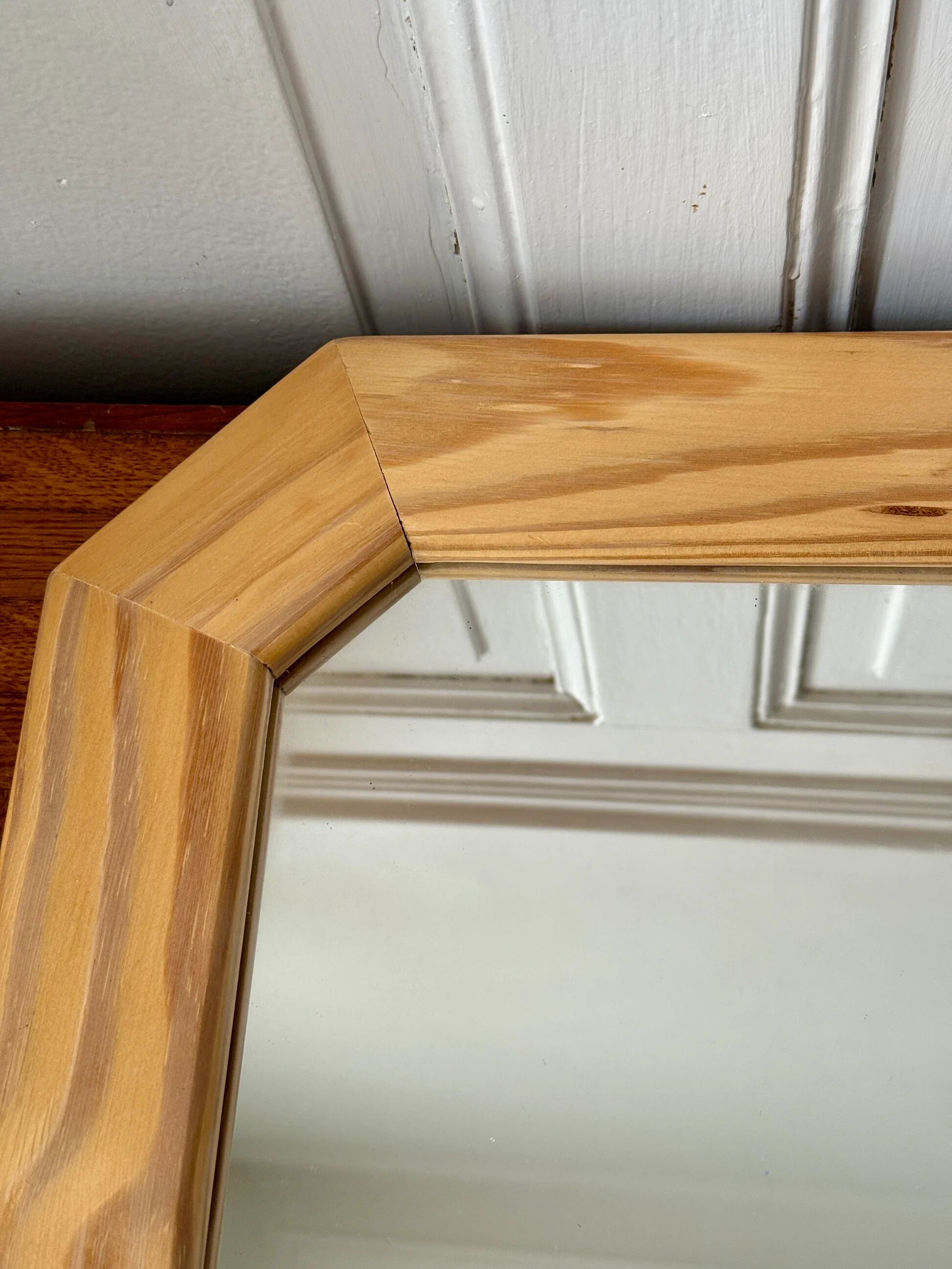 Octagonal mirror in light wood with grooves.