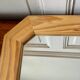 Octagonal mirror in light wood with grooves.