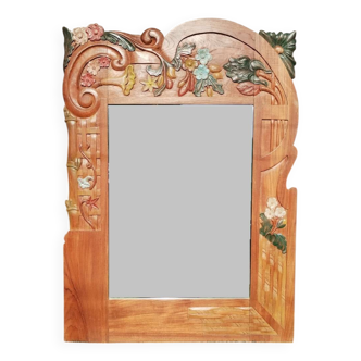 Pretty beveled mirror with wooden frame and floral decoration.