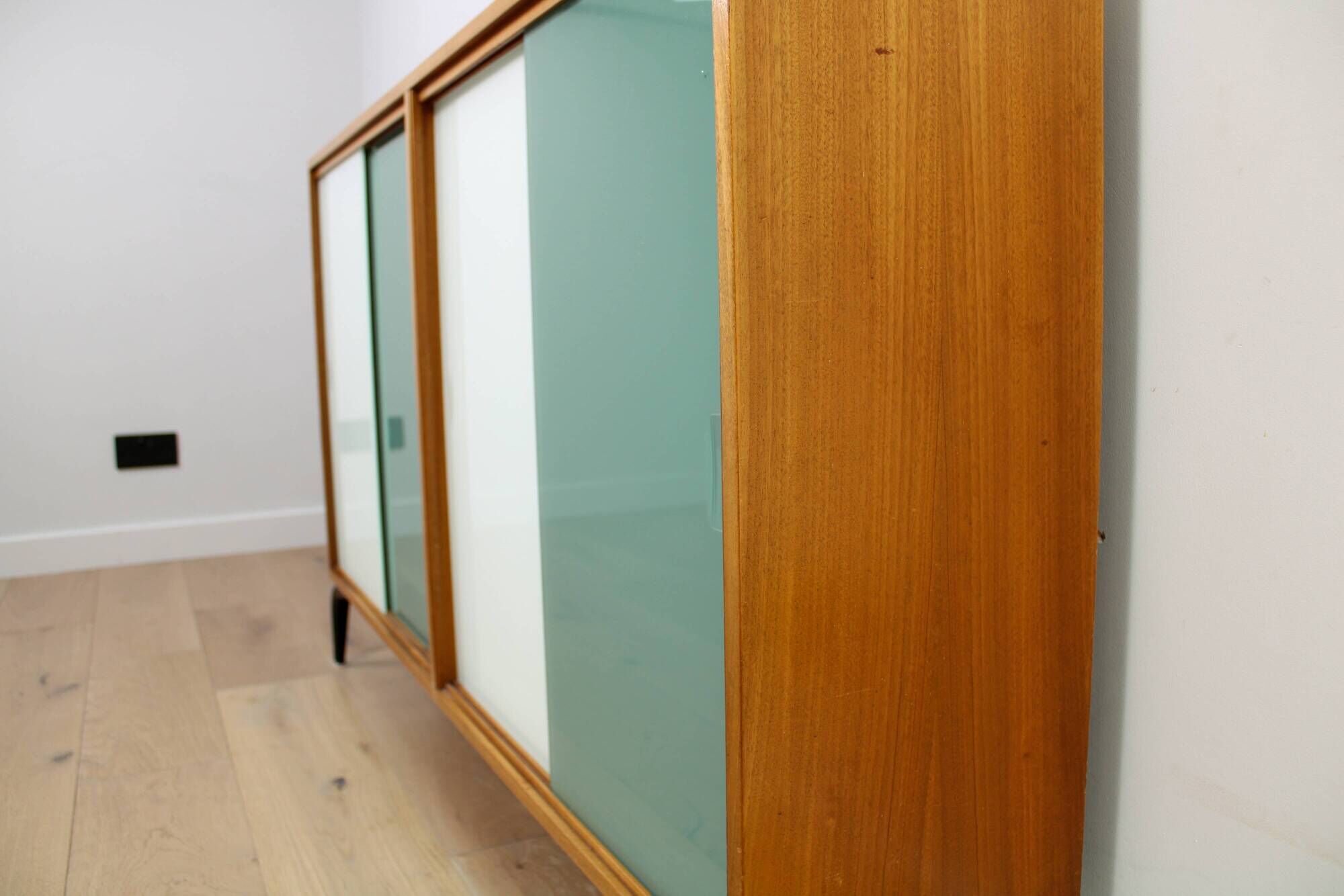 A vintage mid-century bookshelf/sideboard with green and white sliding door