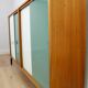 A vintage mid-century bookshelf/sideboard with green and white sliding door