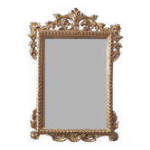 Mirror with a carved wooden frame in an antique style in pure gold.