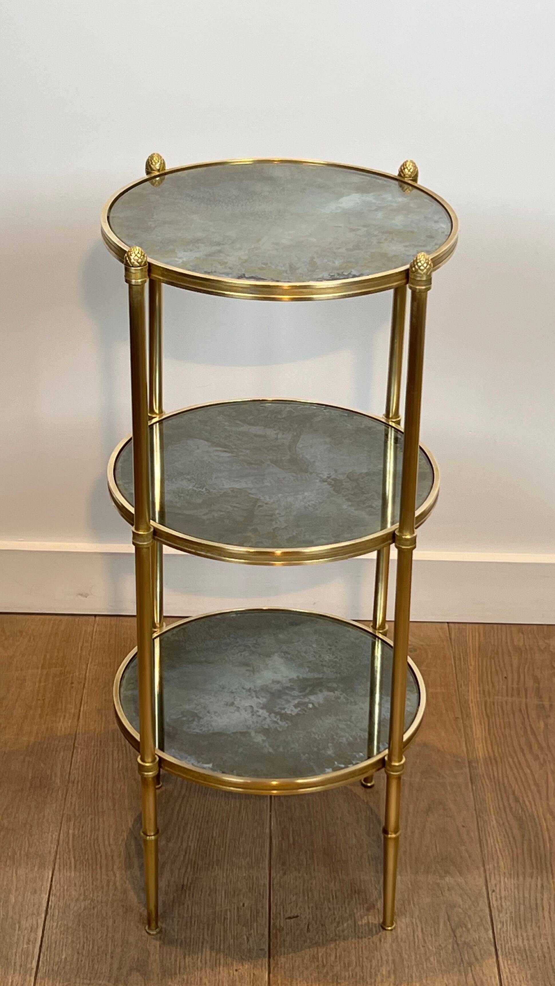 Round bronze side table with triple shelves of églomisé mirrors from Maison Baguès
