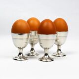 Four silver-plated Christofle egg cups with fluted sides.