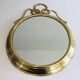 Large decorative oval mirror in brass adorned with a significant twisted bow.