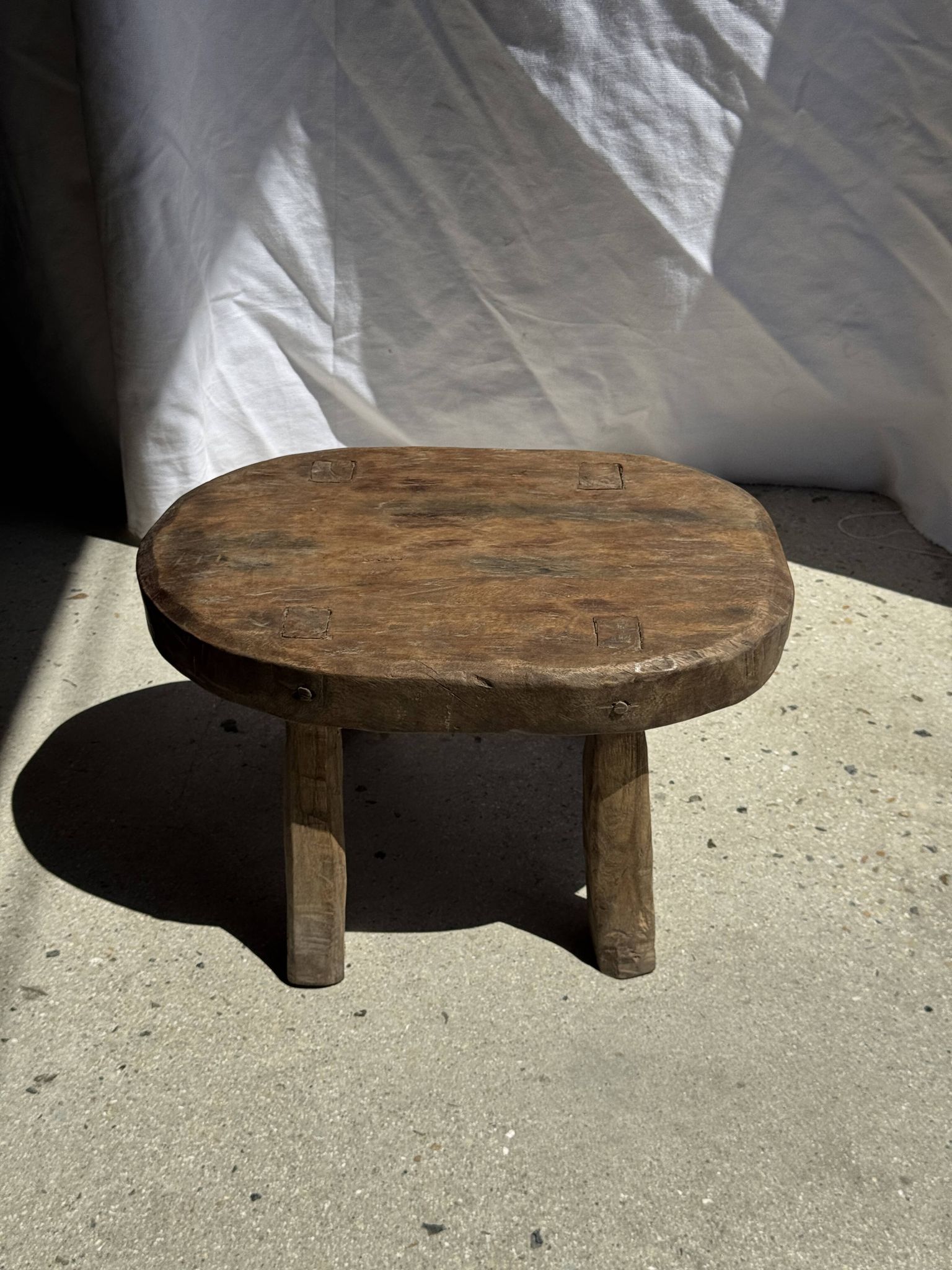 Small stool, oval solid teak side table with curved legs in wabi-sabi style.