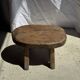 Small stool, oval solid teak side table with curved legs in wabi-sabi style.