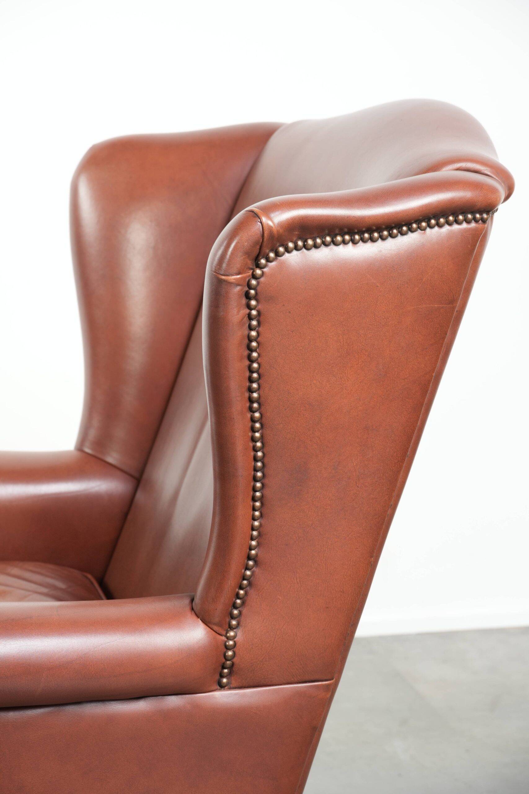 Cognac-coloured cow leather wingback armchair in English style